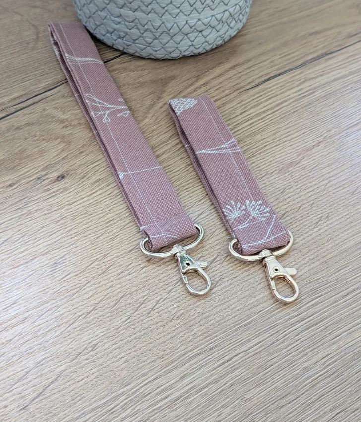 Handgenähtes Schlüsselband in Altrosa mit filigranem weißen Blumenmuster, ausgestattet mit einem goldenen Karabinerhaken.